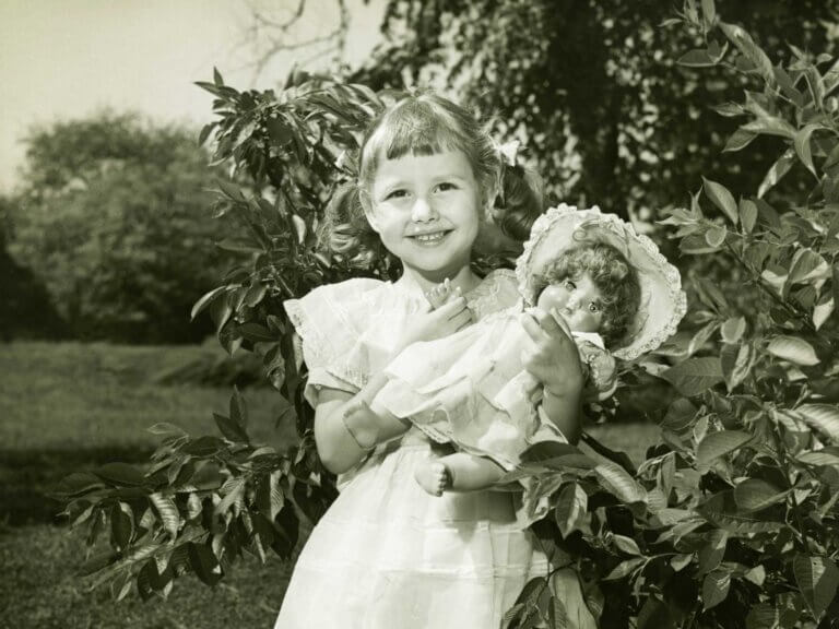 Blank-and-white vintage photo of a young girl holding a doll