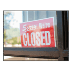 A "Sorry, we're Closed" sign is propped inside of a window